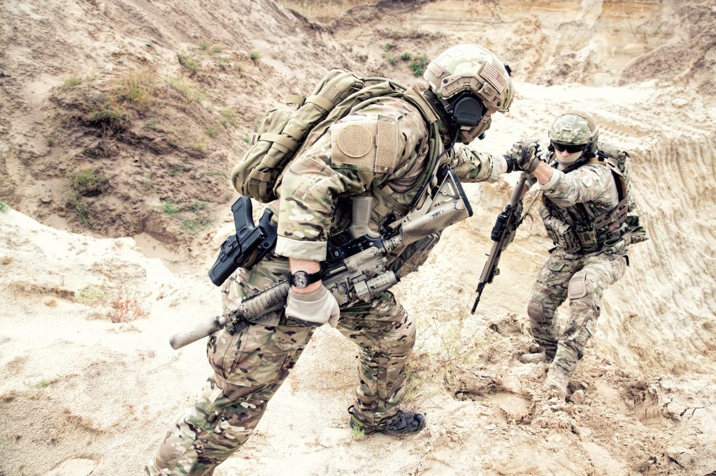 American commando helping friend to climb on dune